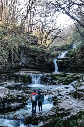 Dan and Beck stand at Sgwd Isaf Clun Gwyn, during one of the best walks in the Brecon Beacons