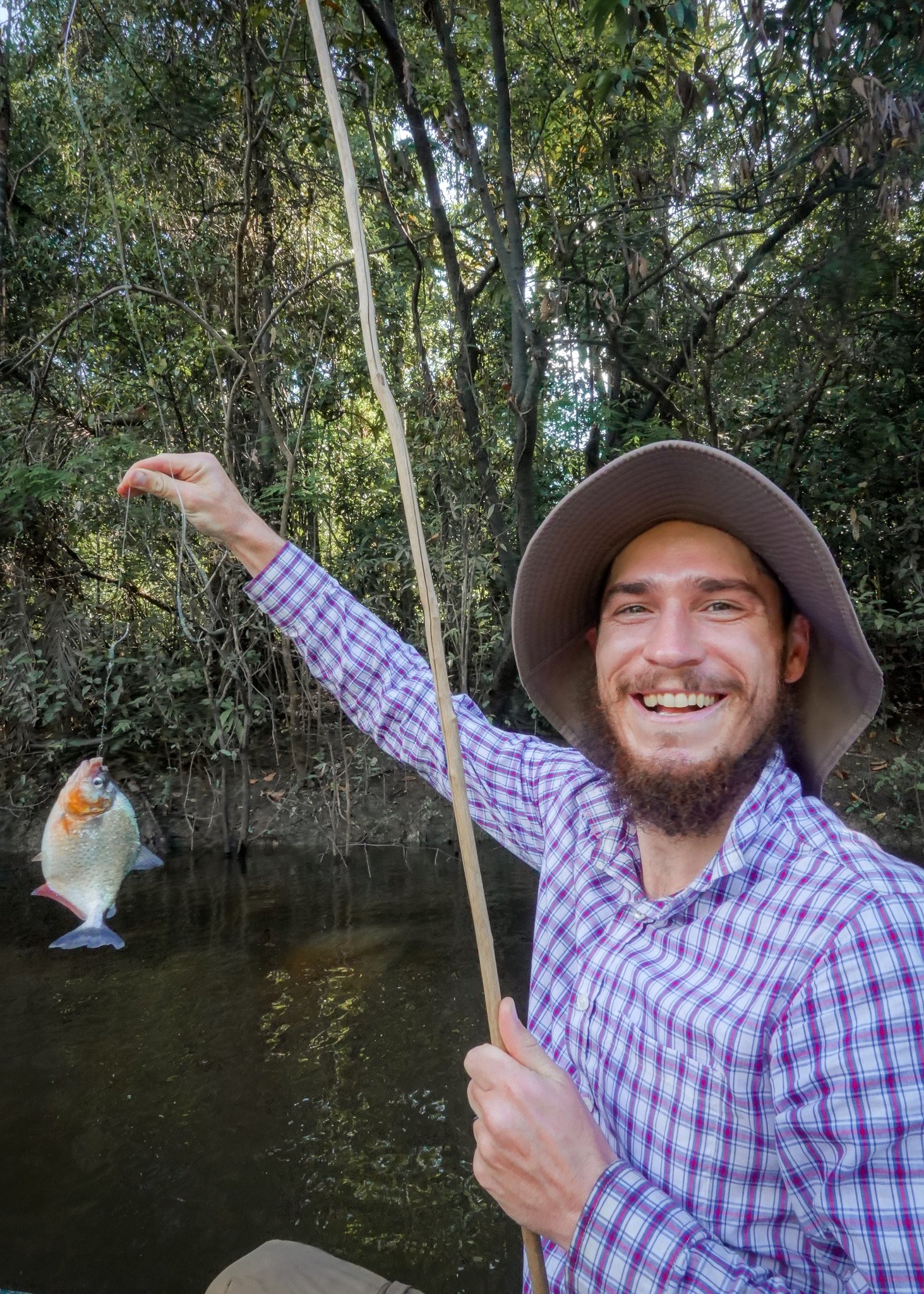 Dan holding a fishing rod, with a piranha attached, on the Tahuayo River, near the Amazon Research Center Lodge
