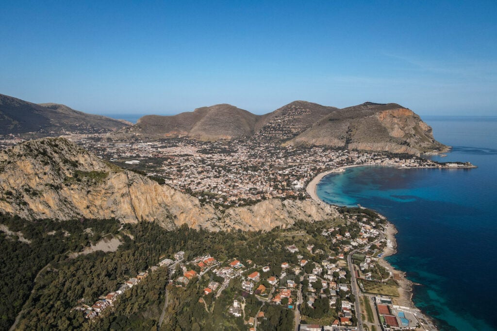Views of the coastline, mountains and a town surrounding a beach from a viewpoint on the Monte Pellegrino Hike