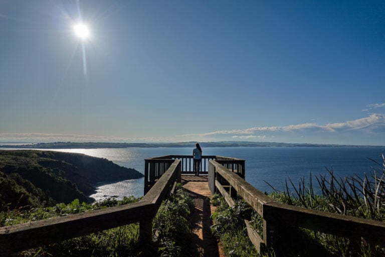 Woman stands at the end of a wooden boardwalk with views across Phillip Island during tours from Melbourne