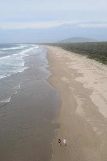 A couple walk together at Seven Mile Beach near Gerroa and its holiday parks (caravan parks)