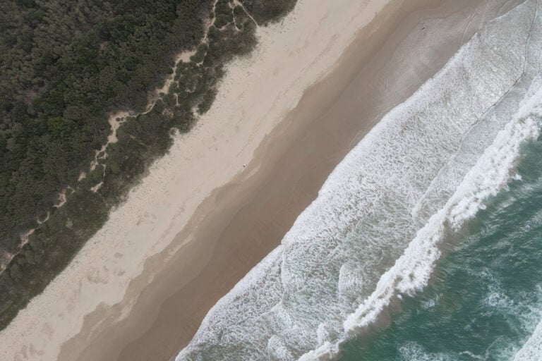 A birds-eye view of a beach called Seven Mile Beach, located in Gerroa, is backed by bushland