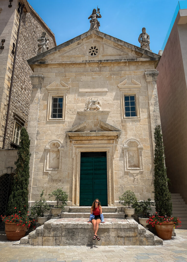 Woman sits on the steps of St.Marks Church at the Heritage Grand Perast Hotel
