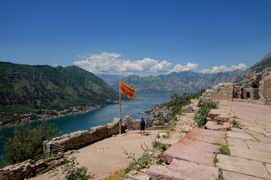 Views across Kotor Bay and surrounding mountains from the top of Kotor Fortress with Montengro flag blowing in the wind