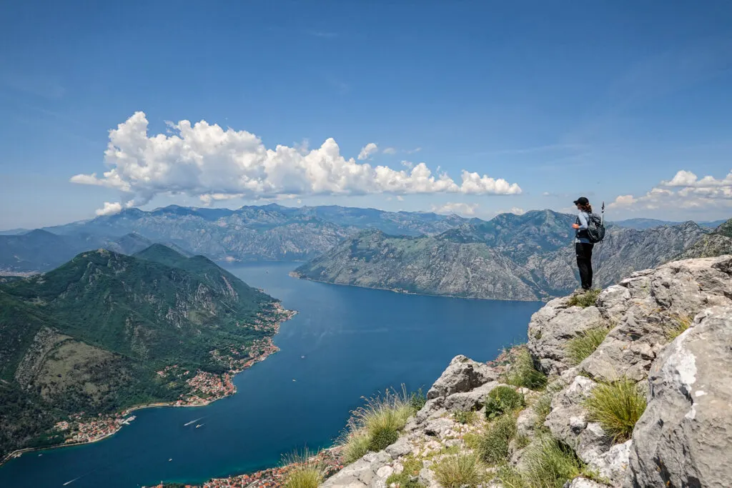 Woman stands on the top of Pestingrad Peak overlooking the bay and surrounding mountains