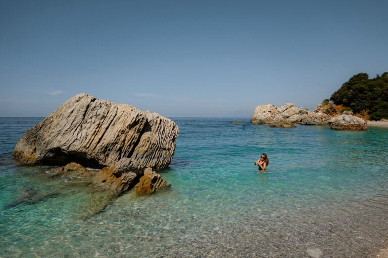 Beck stands and walks with the water of Kroreza Beach up past her waist