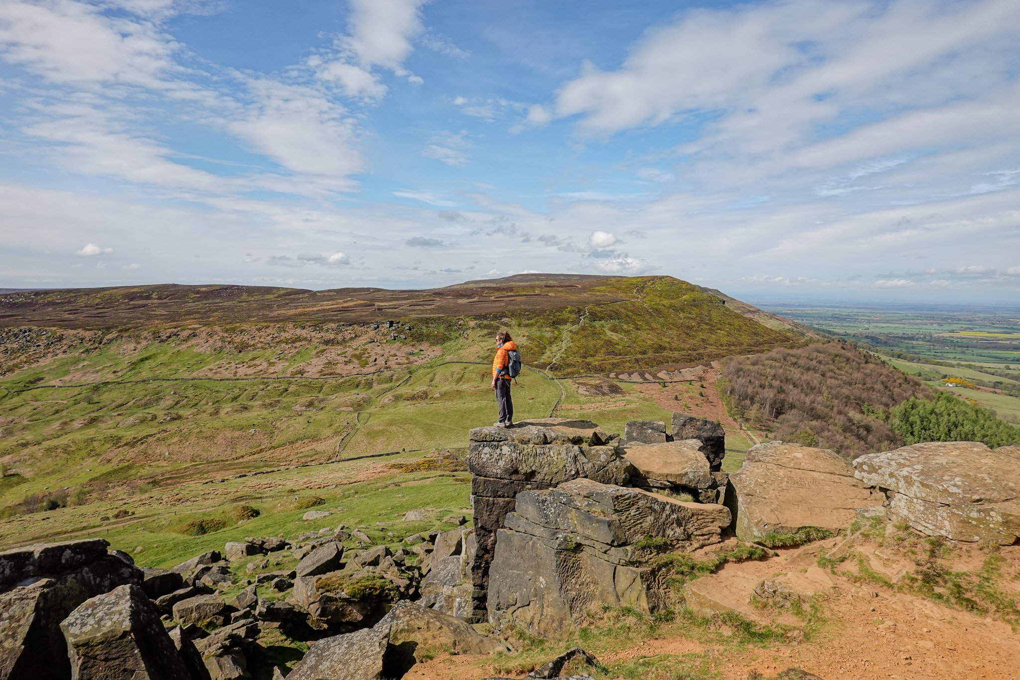Beck stands on one of the sandstone crags overlooking a hill during a walk called the Wainstones Walk