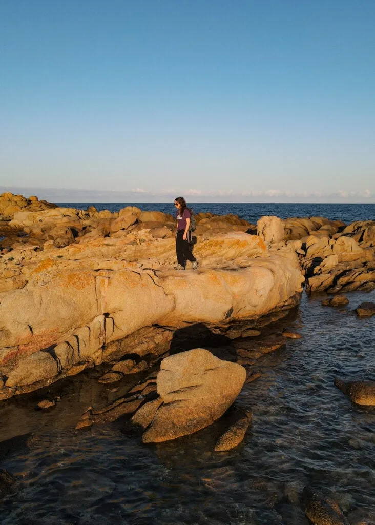 Beck walks near the coast on a rock platform during Sentier Littoral des Bruzzi