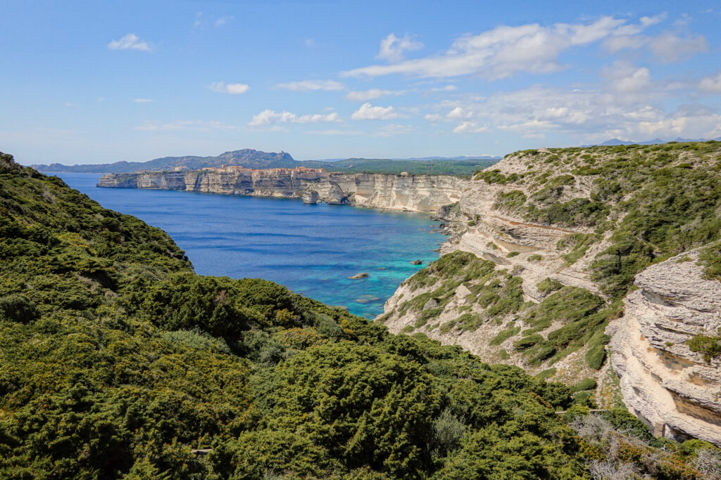 Distant views of a seaside town called Bonifacio surrounded by white cliffs seen from a trail called Campu Rumanilu, which is also known as the Bonifacio Cliff Walk