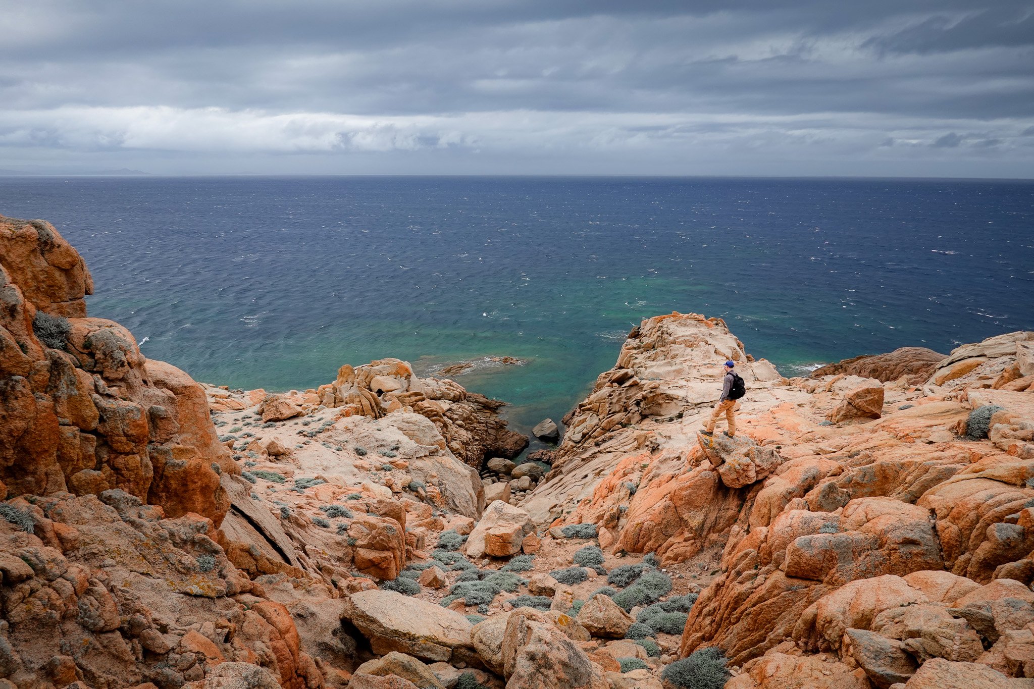 Dan stands on a cape called Capo di Fenu in Bonifacio surrounded by orange coloured rocks after walking along Sentier de Fenu