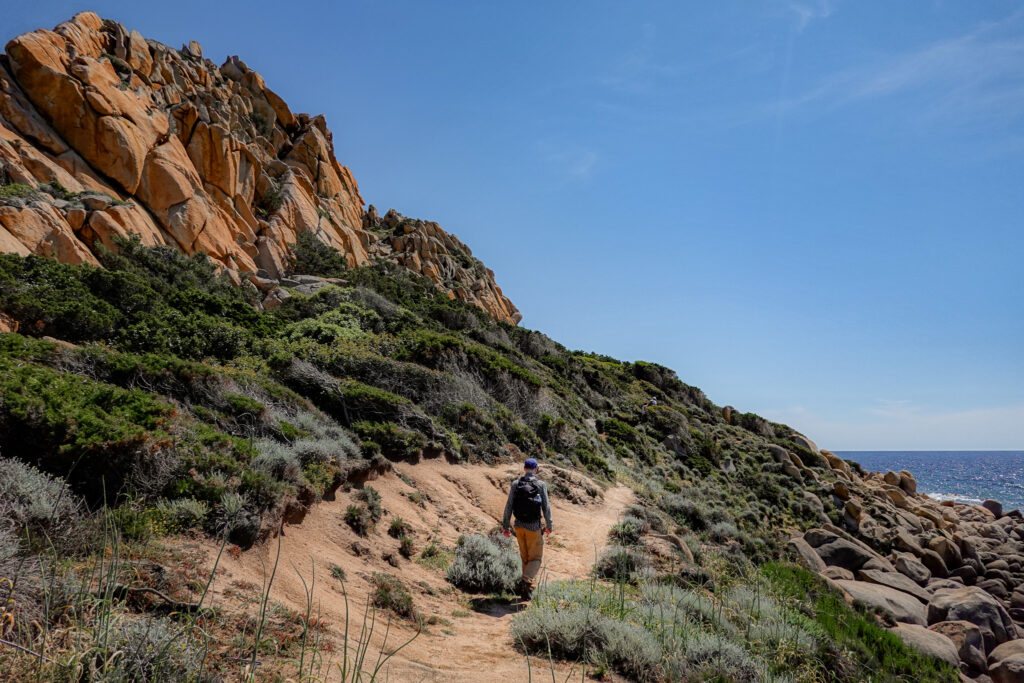 Dan walks by large rock cliff walls on Capu di Muru
