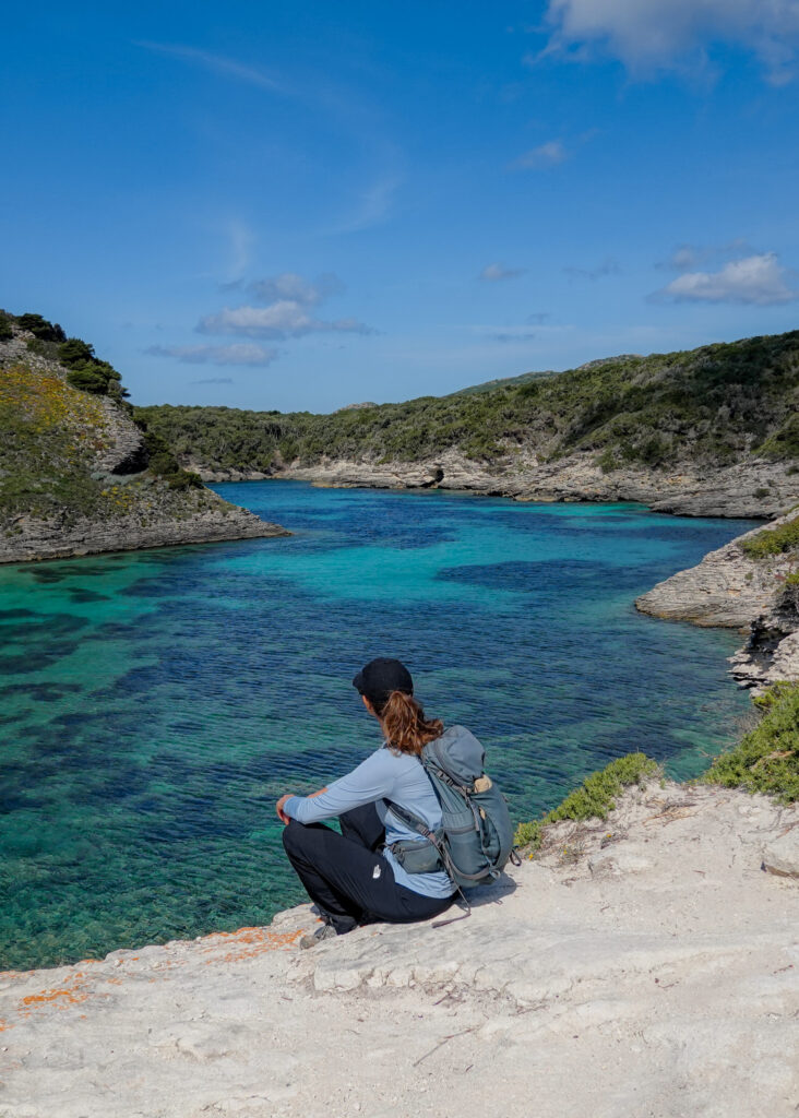 Becks sits on a wide rock platform overlooking a body of water