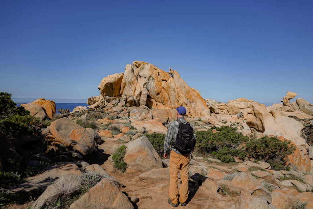 Dan stands on a rocky coastline during a walk in Corsica called Sentier du littoral de Campomoro