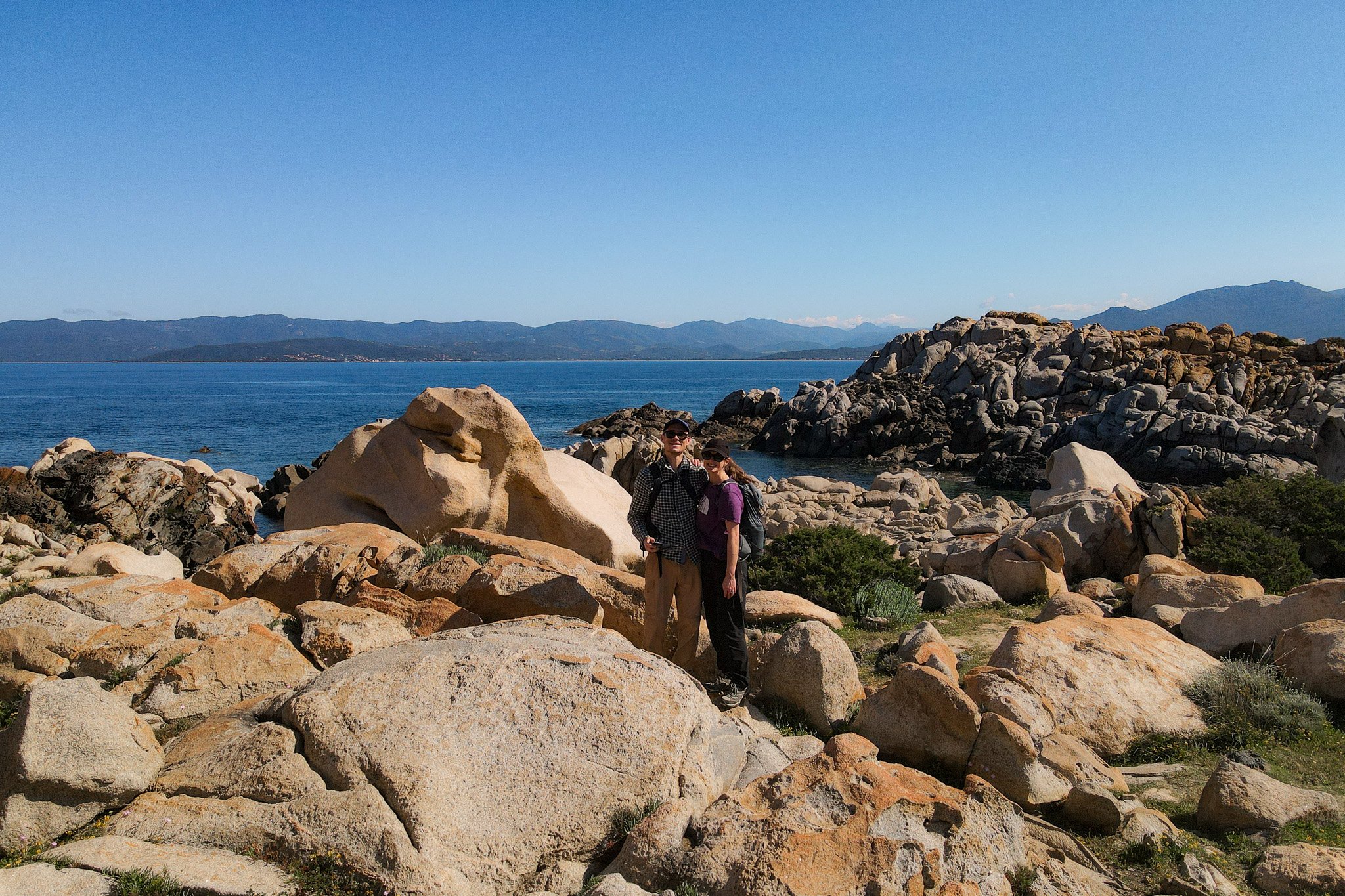 Dan and Beck embrace near a rocky coastline during a walk in Corsica called Sentier du littoral de Campomoro