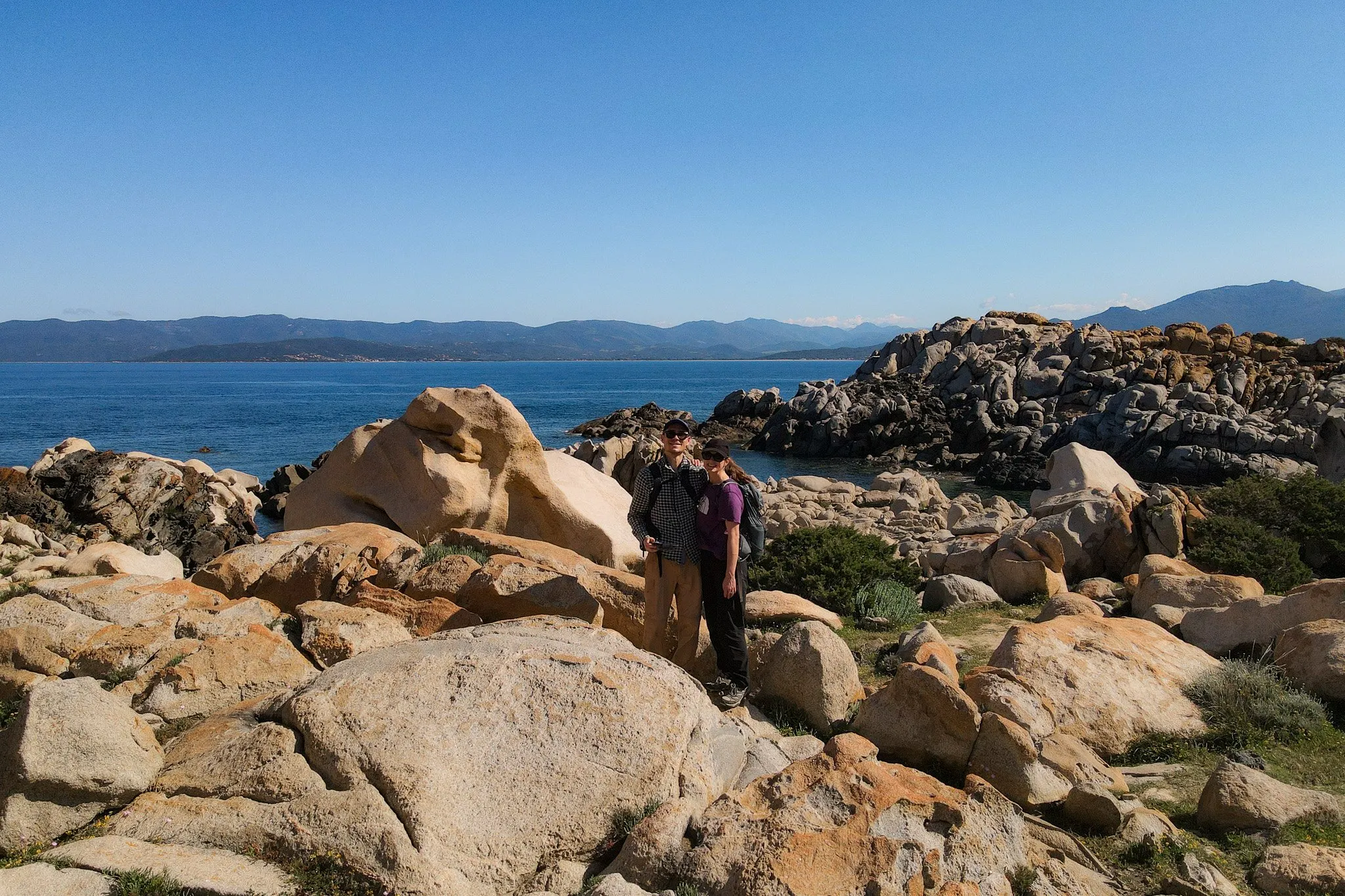 Dan and Beck embrace near a rocky coastline during a walk in Corsica called Sentier du littoral de Campomoro