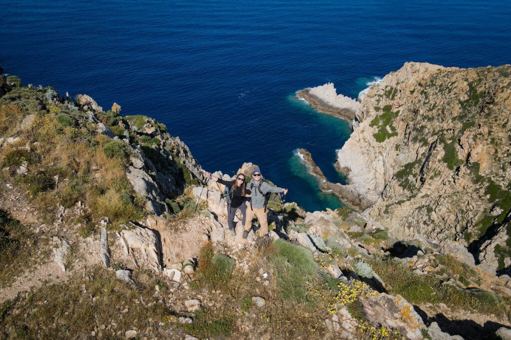 Beck and Dan stand near a cliff's edge on Pointe de la Revellata
