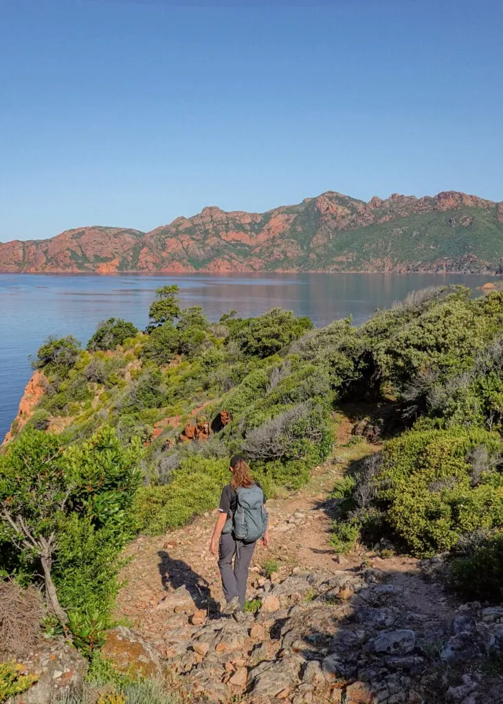 Beck descends a rocky  coastal trail in Corsica called Sentier du Facteur Girolata
