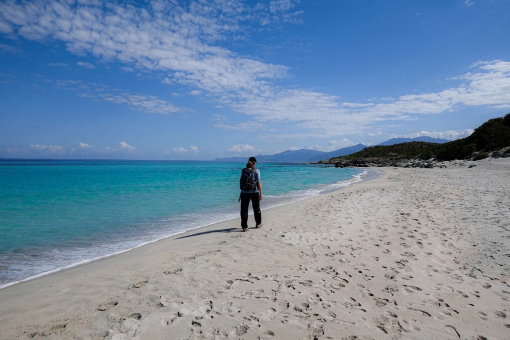 Beck walks on a white sand beach called Saleccia Beach at the start of a walk called Sentier des Douaniers Saint-Florent
