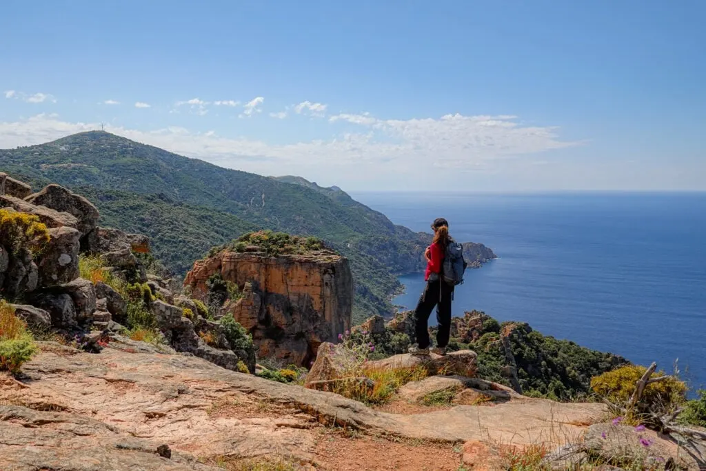 Beck stands near an impressive rock formation on a walk called Sentier du Château Fort Piana