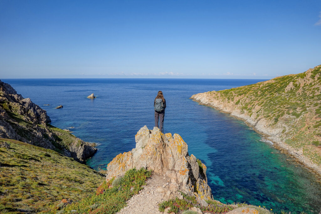Beck stands on a rock overlooking the sea on Pointe de la Revellata