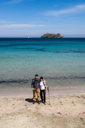 Dan and Beck embrace on a beach during a walk in Corsica called Sentie de Douaniers Cap Corse