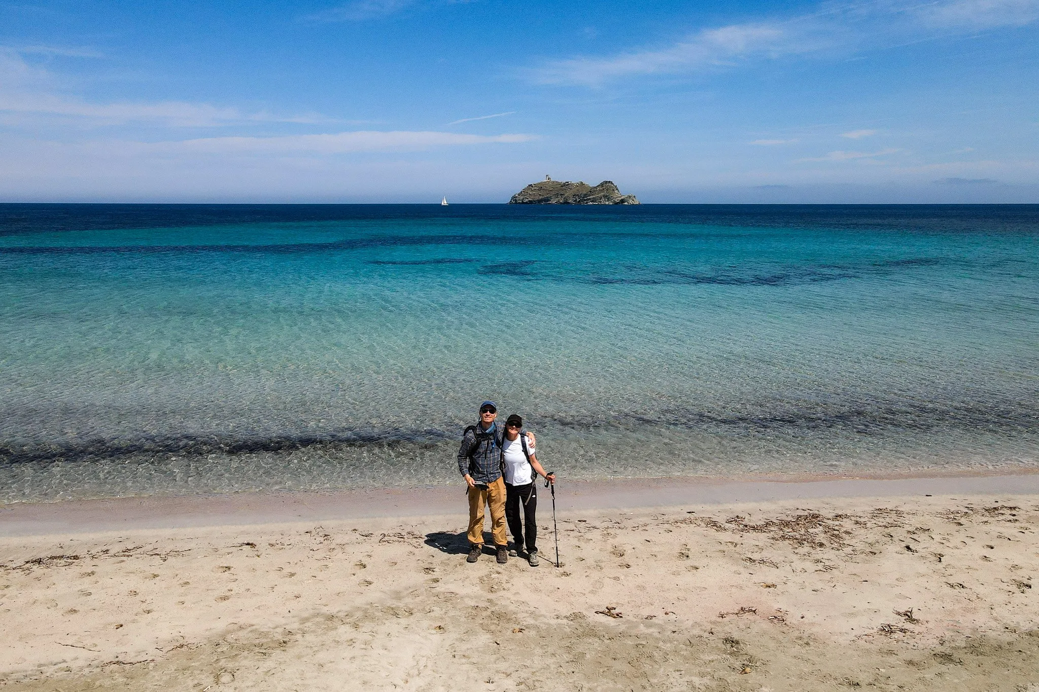 Dan and Beck embrace on a beach during a walk in Corsica called Sentie de Douaniers Cap Corse