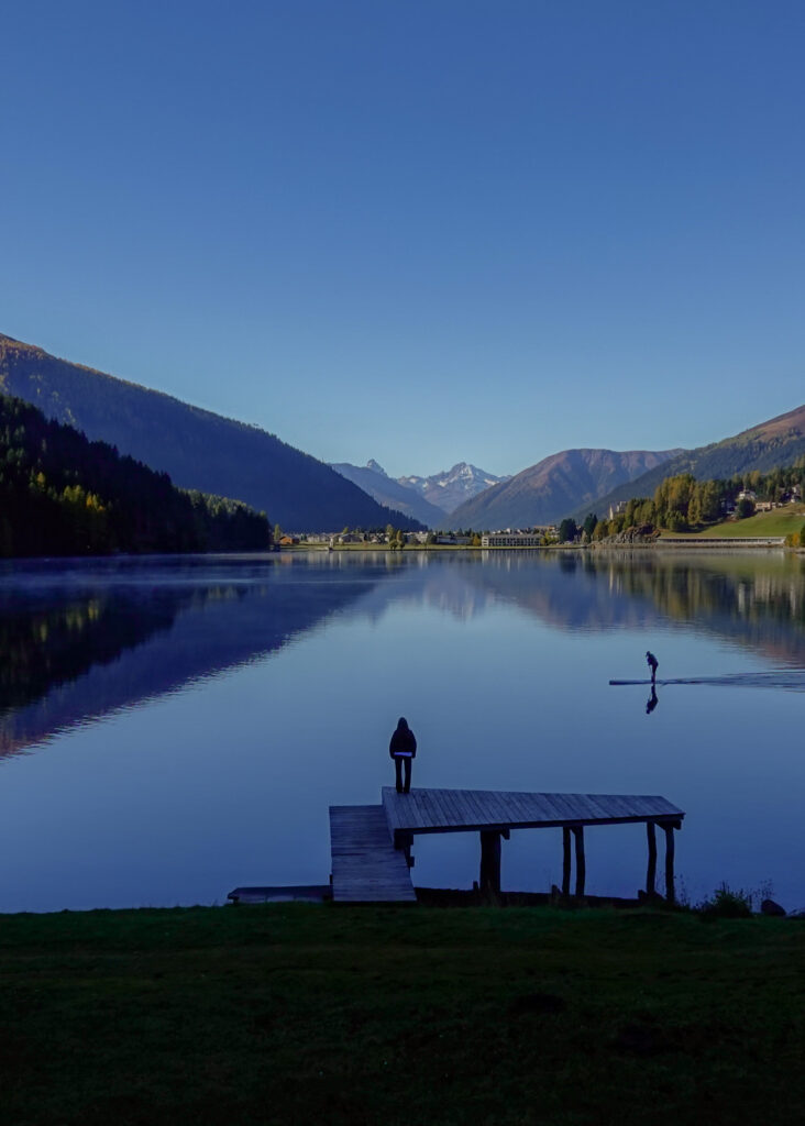 Beck stands on a wooden jetty near the lake during a walk called Davosersee Rundweg (AKA Lake Davos Trail)