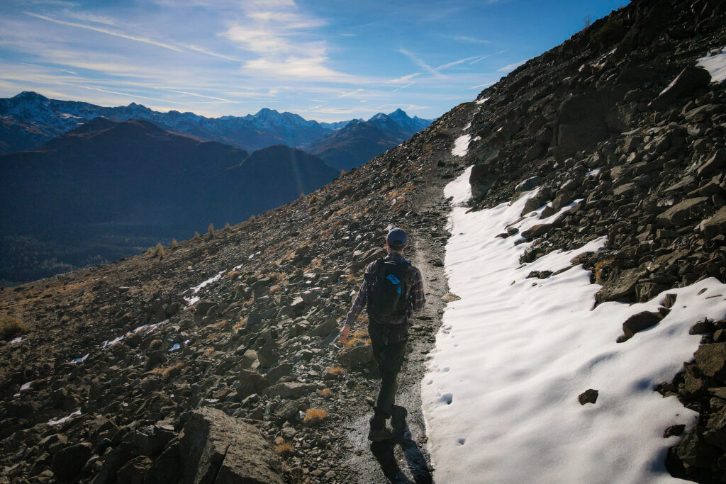 Dan walks by some snow amongst rocky terrain on the Davos Panoramaweg