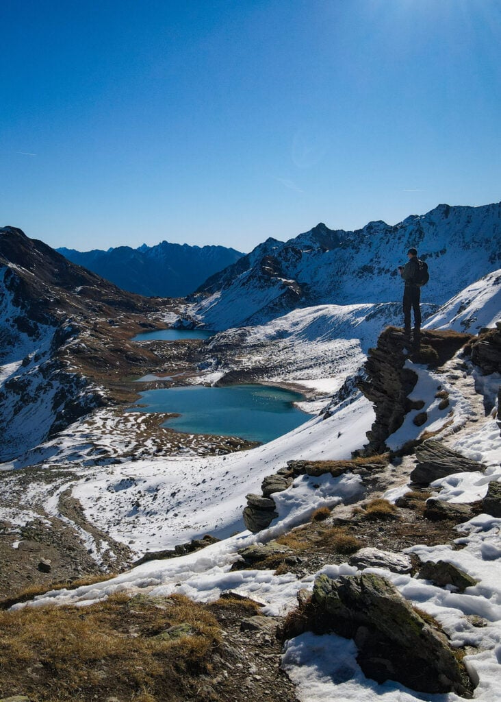 Dan stands on a rock platform, overlooking Alpine lakes