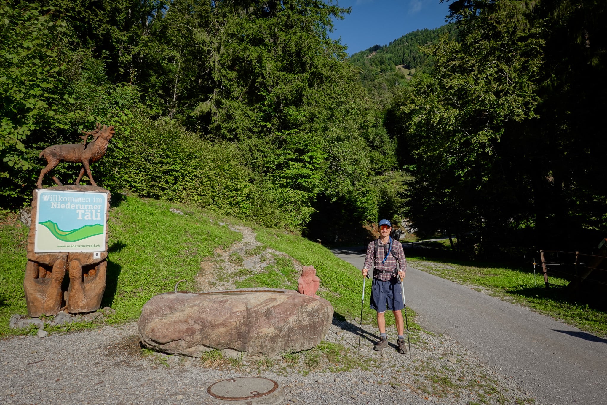Dan stands at the trailhead for the Hirzli Planggenstock Hike by a forest