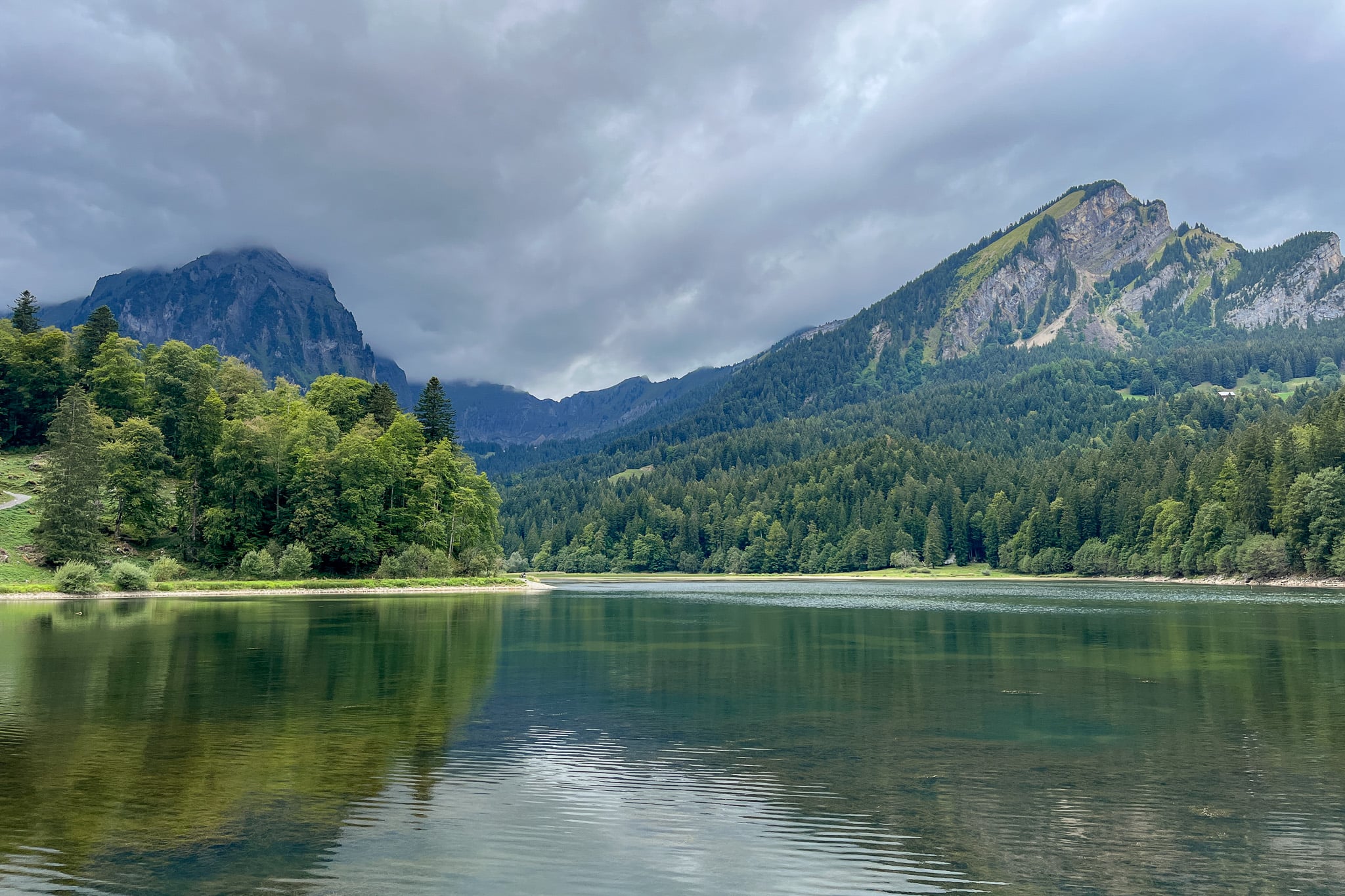 A lake called Obersee Lake is dwarfed mountains in an area called Näfels and can be seen as part of a hike called Ahornen Rundweg