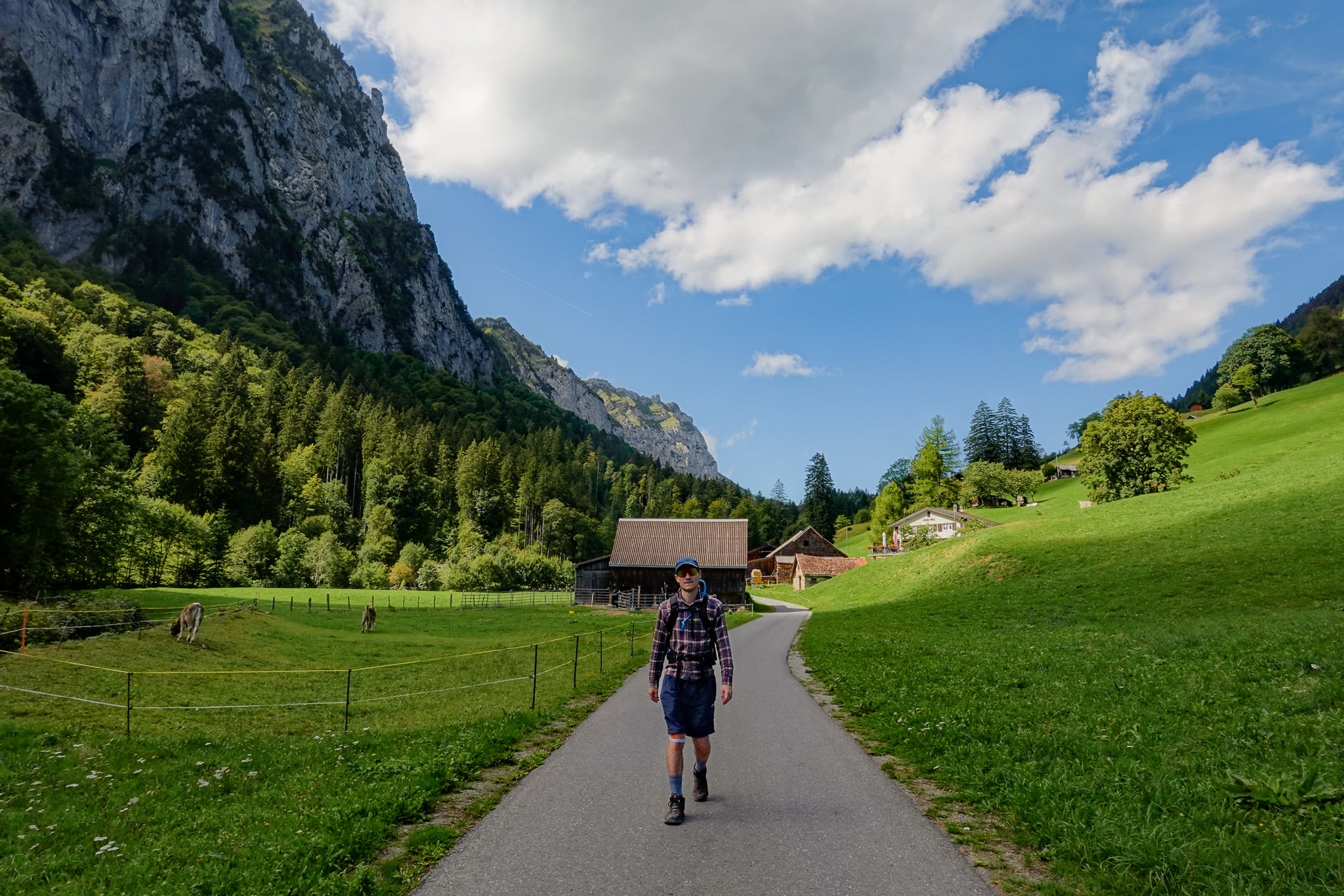 Dan walks on a paved road in a valley called Niederurnen Täli during the Hirzli Planggenstock Hike