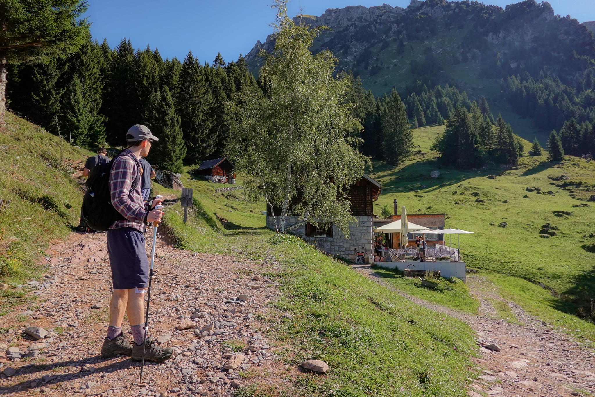 Dan looks at a restaurant amongst a green pasture during a walk called Holzflue Rundweg