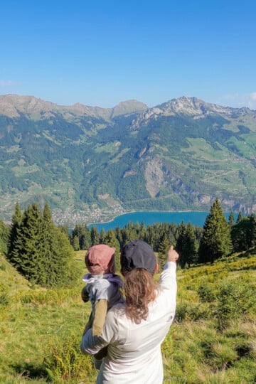Beck and baby look toward a lake during a hike called the Schabziger Höhenweg