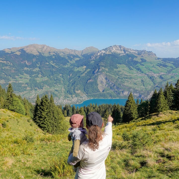 Beck and baby look toward a lake during a hike called the Schabziger Höhenweg