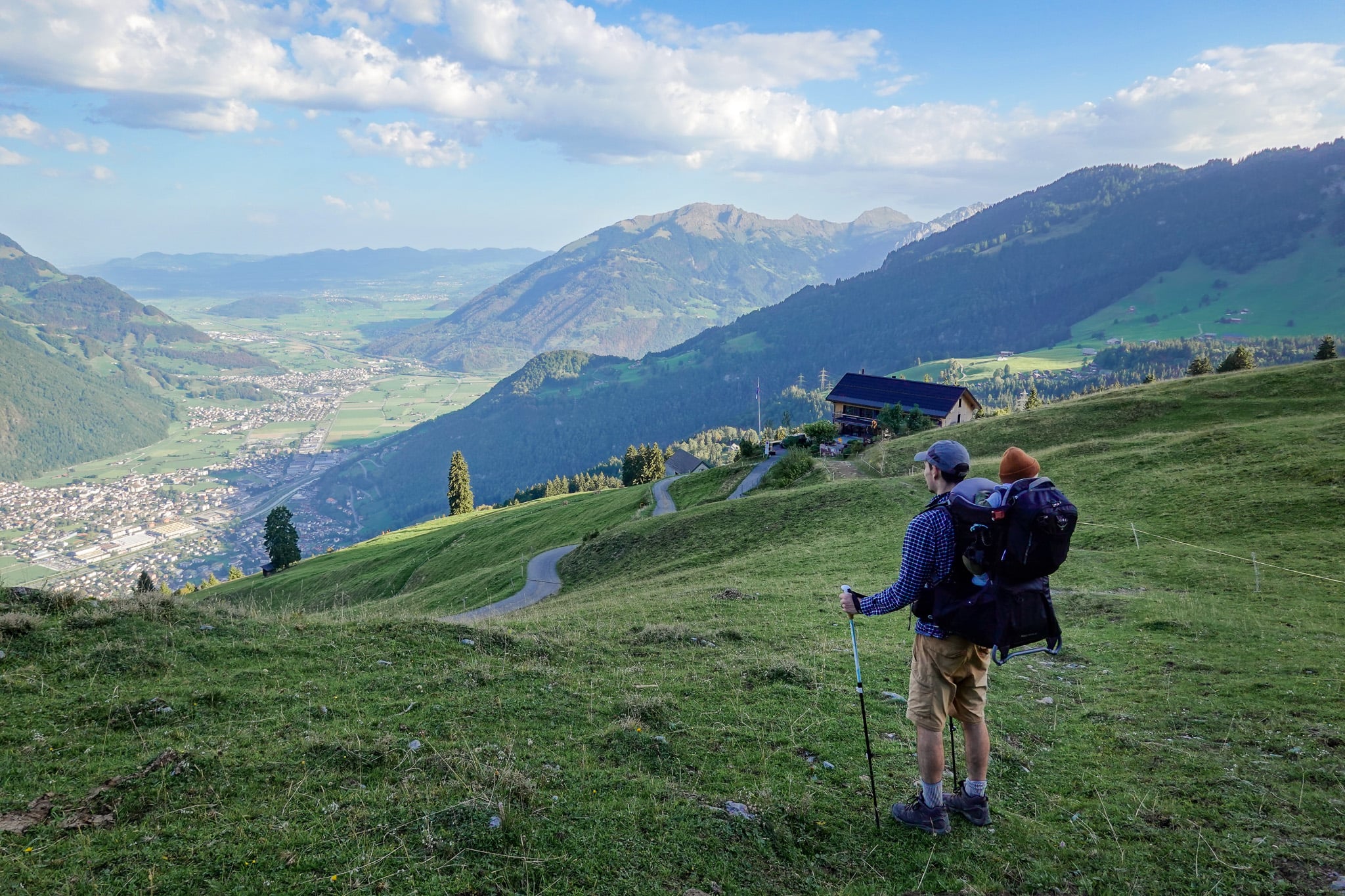 Dan with a child carrier back pack looks towards a valley during a walk called Schabziger Höhenweg